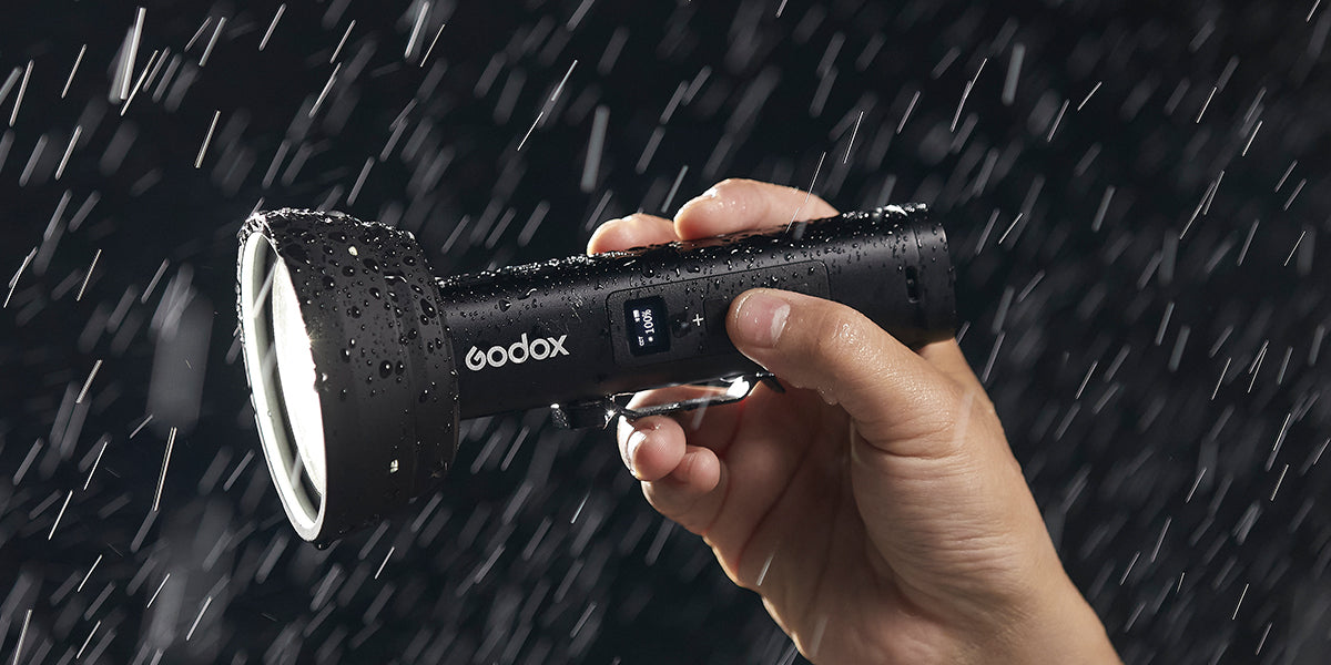 Людина тримає Godox FL15Bi під дощем, демонструючи його водозахисний рейтинг IP54