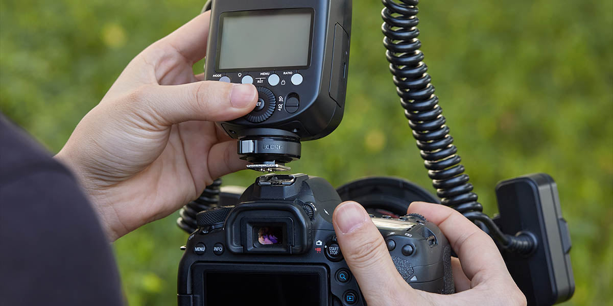 Фотограф кріпить Godox MF-T76 на гарячий башмак своєї камери Фотограф кріпить Godox MF-T76 на гарячий башмак своєї камери